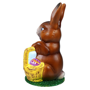 Ino schaller sitting brown ceramic easter bunny holding yellow woven basket with purple egg on green base