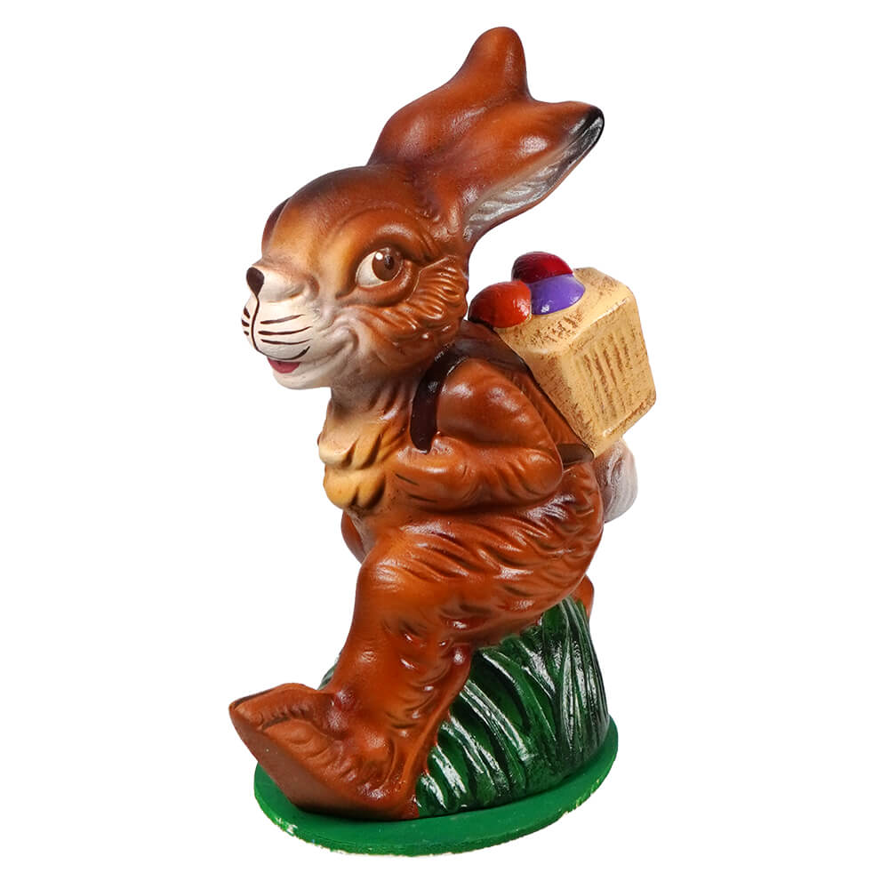 Ino schaller walking brown ceramic easter bunny carrying a basket of colorful eggs on green base