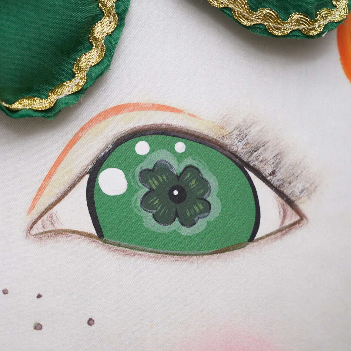A close-up of the ireland zombinaland decorative pillow featuring a green eye with a four-leaf clover iris by tracy scheff