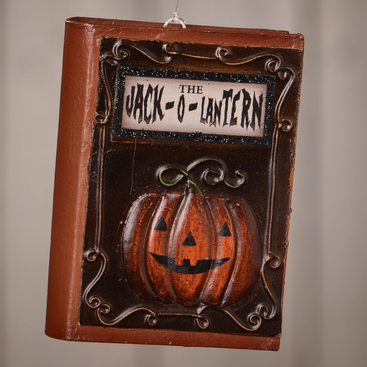 Brown bethany lowe jack o lantern book ornament with carved orange pumpkin and dark brown scrollwork frame
