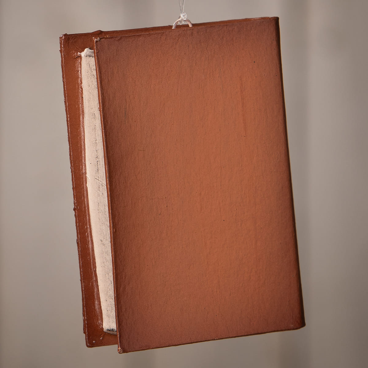 Brown leather-bound jack o lantern book ornament by bethany lowe hanging by a string for halloween decor