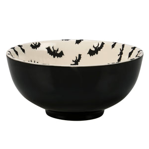 Black ceramic jack o’lantern bowl with white interior and black bat silhouettes part of a spooky bowl set