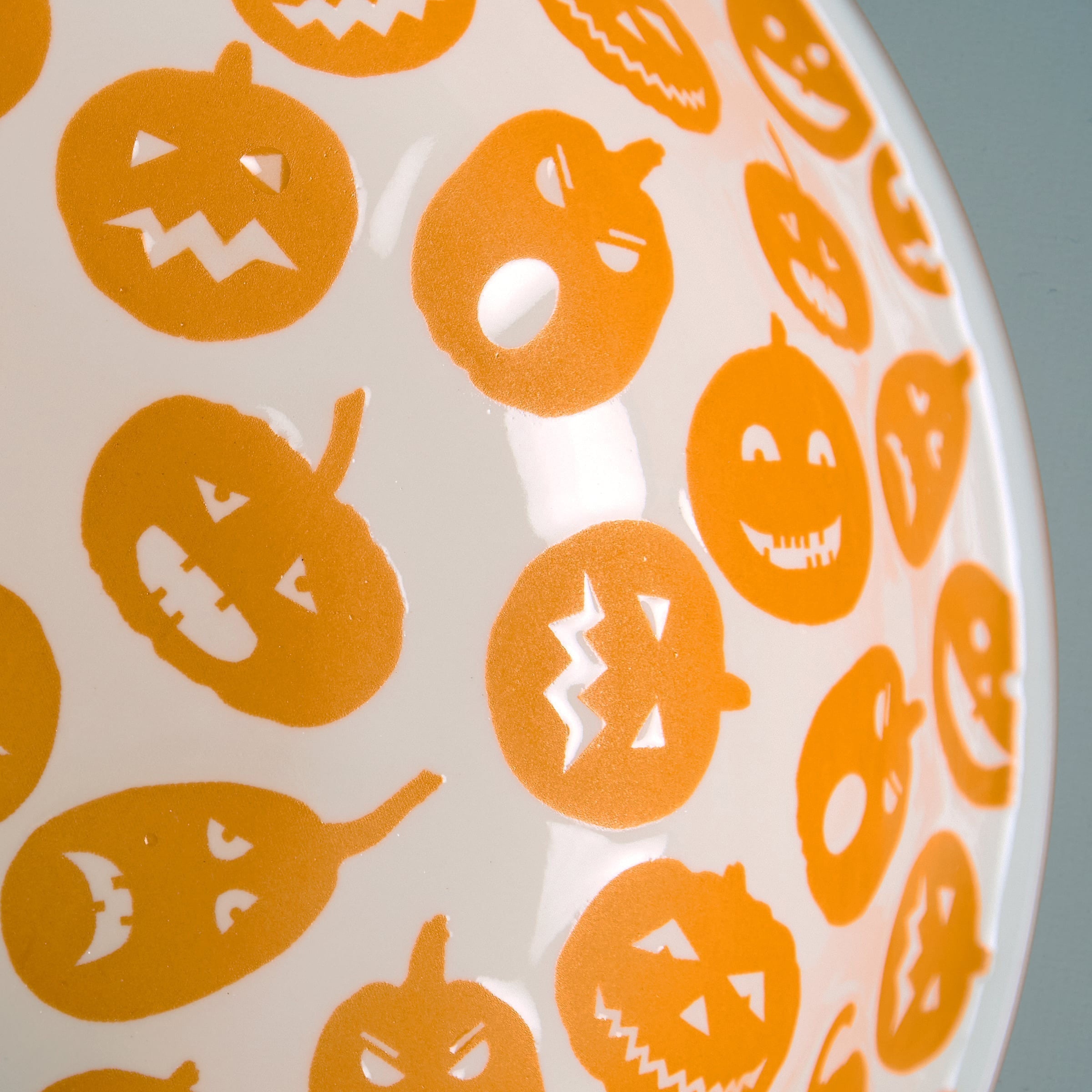 White ceramic jack o lantern bowl set featuring orange pumpkin faces with different expressions for fall decor