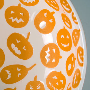 White ceramic jack o lantern bowl set featuring orange pumpkin faces with different expressions for fall decor