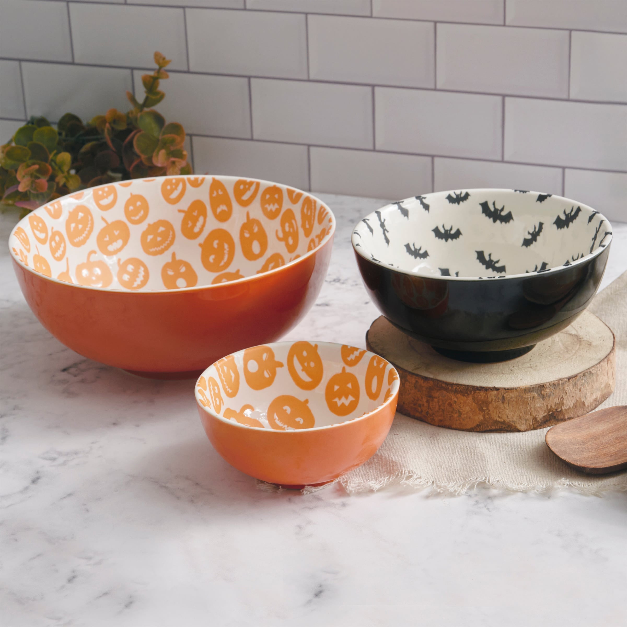 Set of three orange ceramic jack o lantern bowl set with white interiors featuring pumpkin and bat patterns