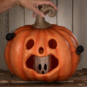 Jackie boo lantern halloween pumpkin with carved face, black spiders, and ghost figurine inside as a jack o lantern