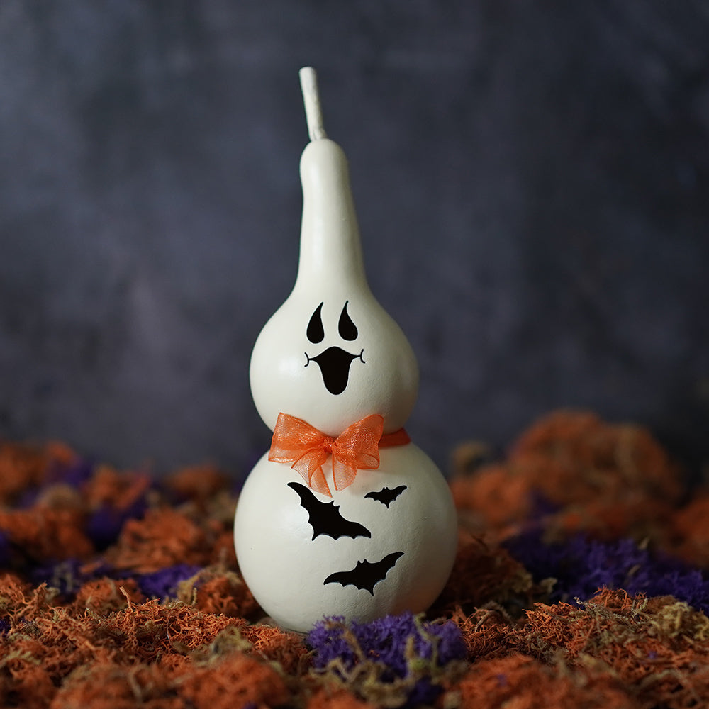 White painted tiny ghost gourd with black ghost face and bats tied with orange ribbon made by family owned meadowbrooke gourds natural paper mache