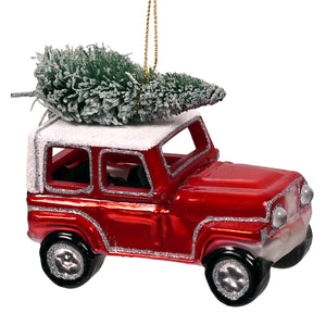 Red glass jeep hauling christmas ornament shaped like vintage suv with silver glitter trim hauling christmas tree on roof