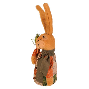 A plush tan jeffrey rabbit holding carrot figurine wearing an apron with orange polka dots and green leaf motifs