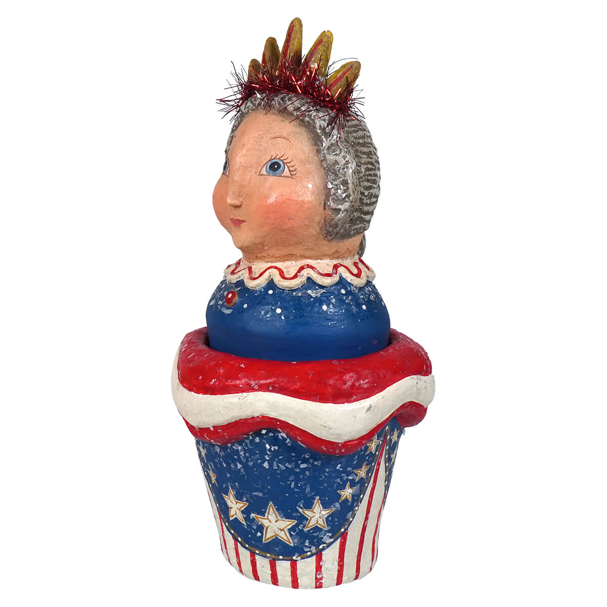 A whimsical ceramic johanna parker lady liberty container shaped like a red white and blue cupcake with a crowned girl inside