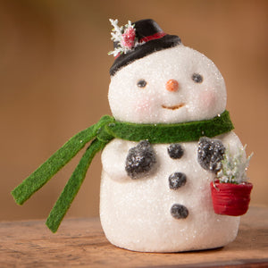 A charming white glittery snowboy figurine with black top hat, green scarf holding red potted plant by Bethany Lowe Designs