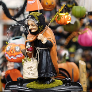 A just a wee bit wicked witch figural decor by bethany lowe with mossy green hair and an orange cloak holding a pumpkin lantern