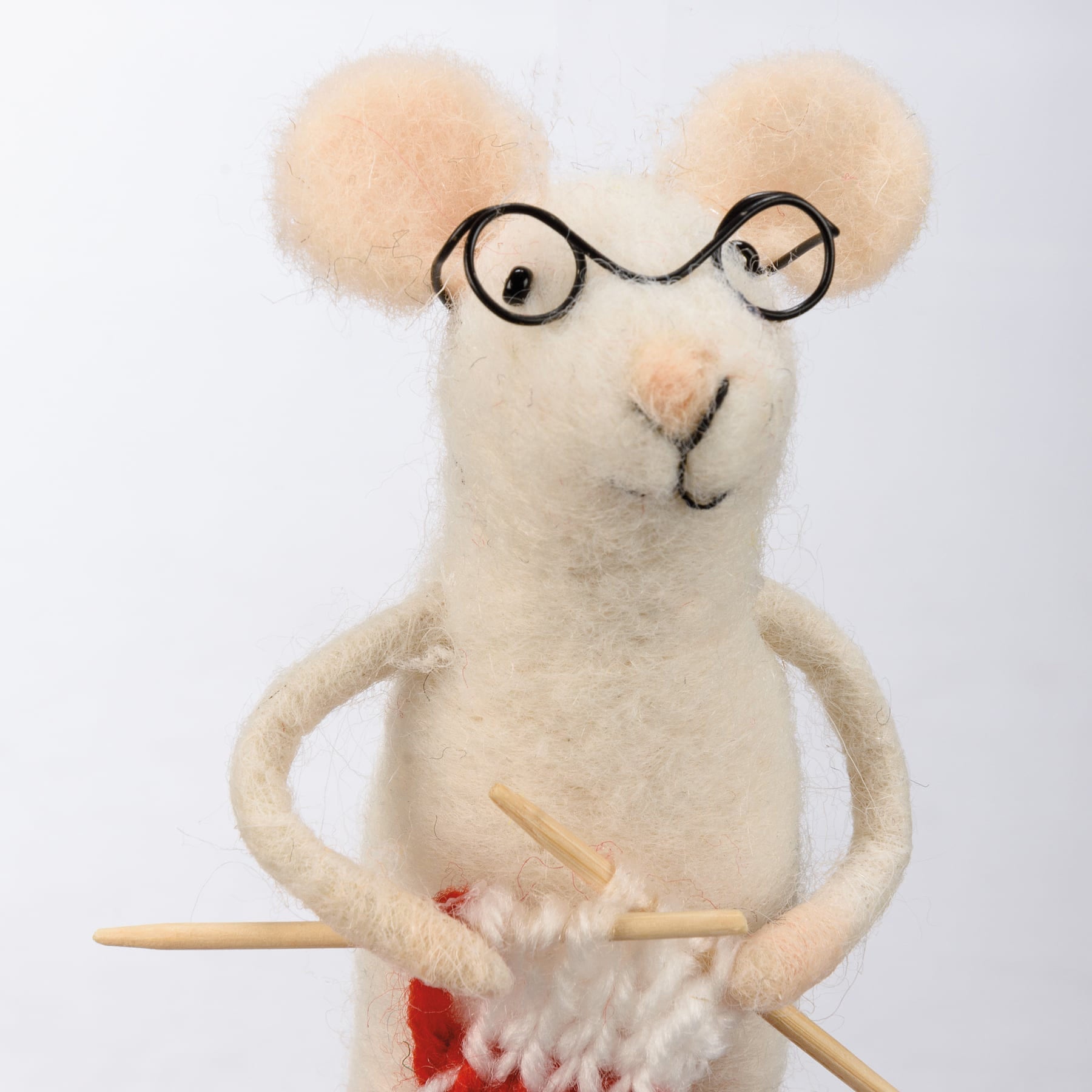 A charming cream-colored felt merry mouse critter wearing black-rimmed glasses and holding wooden knitting needles
