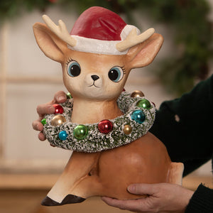A charming tan ceramic christmas reindeer figure by bethany lowe wearing a santa hat with festive wreath decor