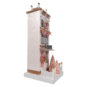 A delicate pink and white miniature house ornament called le salon by cody foster with glittery details and festive wreaths