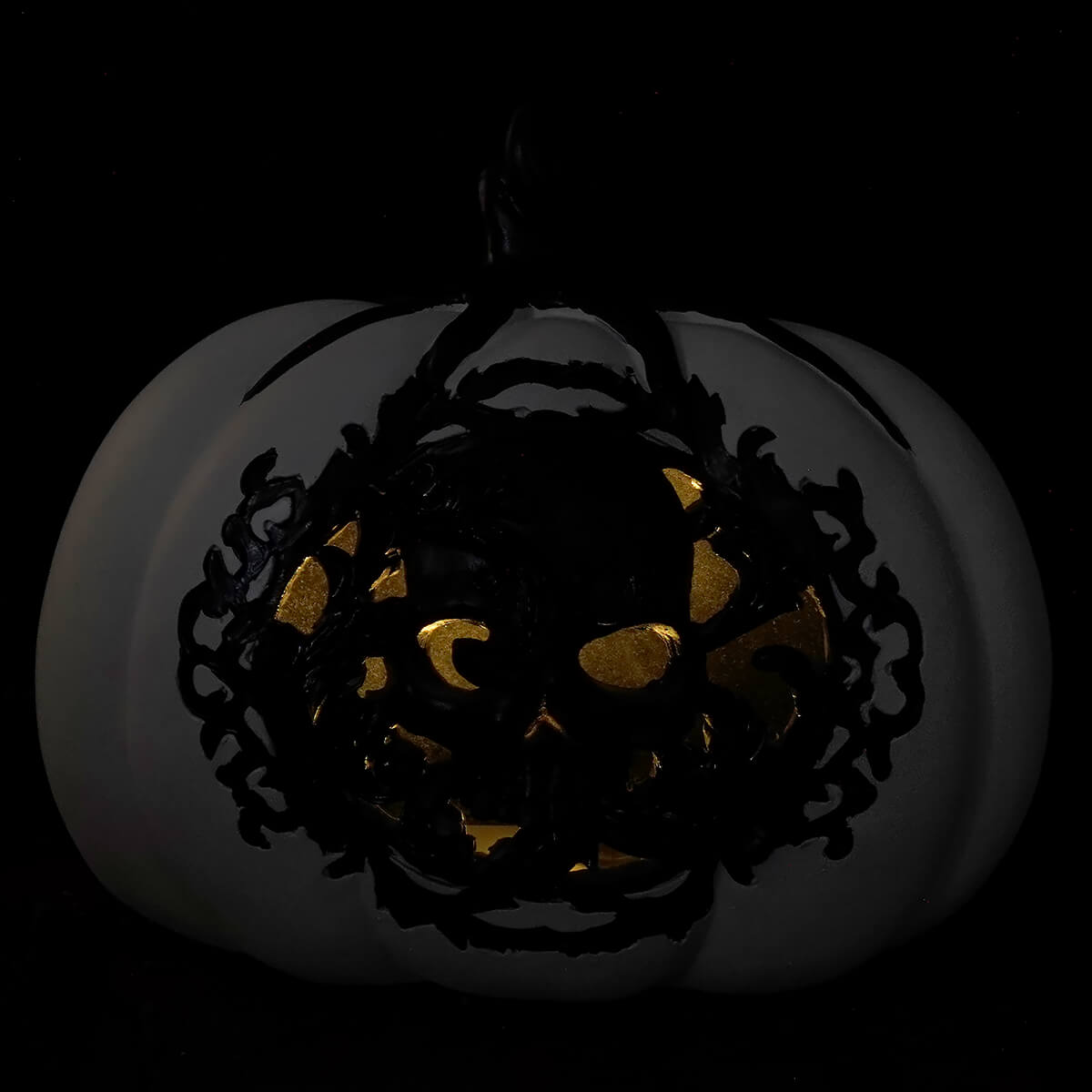 Jack-o’-lantern with an intricate black design carved into its face, illuminated from within.