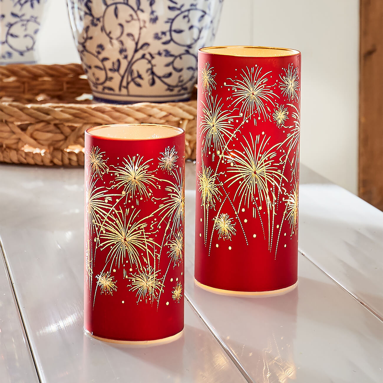 Red cylindrical candle holders decorated with gold firework designs.