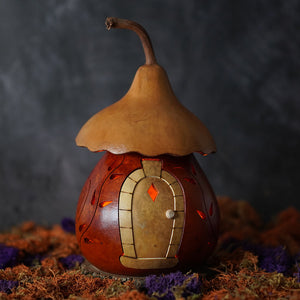 Hand-carved lighted harvest cottage gourd with rustic pumpkin shape warm amber glow and natural stem roof by meadowbrooke gourds