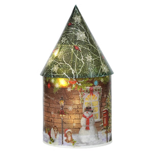 A festive green house luminary with timer featuring a cozy paper design, glowing holiday lights, and snow-dusted roof