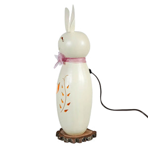 Cream-colored ceramic tall white poppy bunny lamp with pink bow and orange leaf decals on wooden slice base