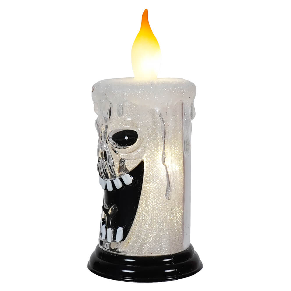 Spooky skull-shaped candle with a glowing flame on top.