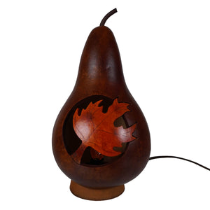 Dark brown pear-shaped lighted maple leaf silhouette gourd lamp with carved orange leaf design and black stem unique artisan piece