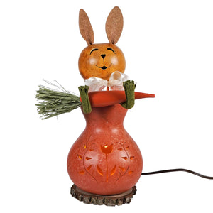 A charming orange willow bunny gourd lantern with tulip cutouts holding a carrot glowing warmly when lit