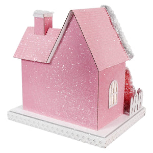 Pink cardboard house with snow-like glitter and a white picket fence.