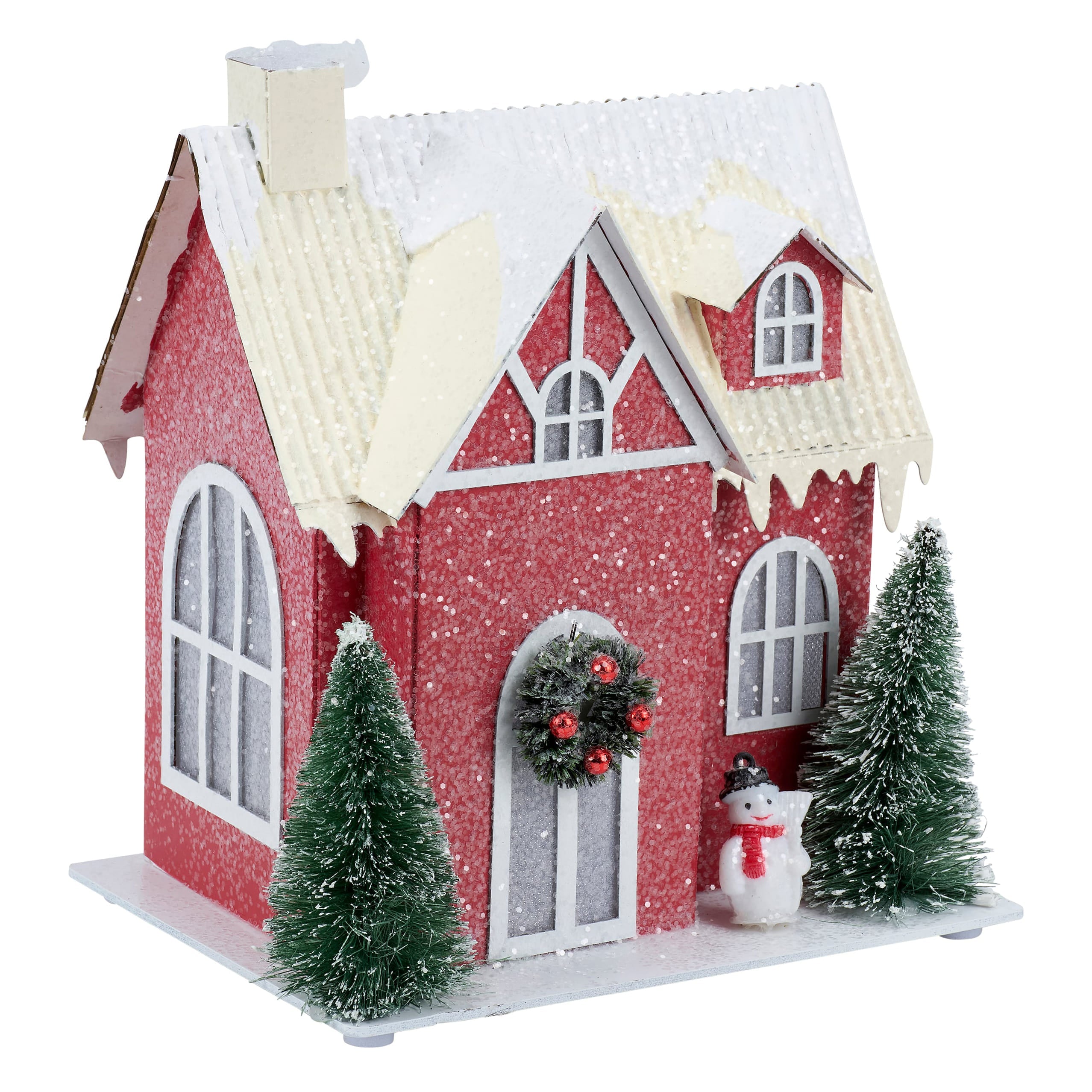 A festive lighted red house sitter with glittery red exterior snow-dusted roof and miniature pine trees and snowman