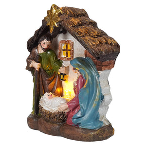 Lighted resin holy family manger scene with painted resin figures and glowing light inside thatched roof manger