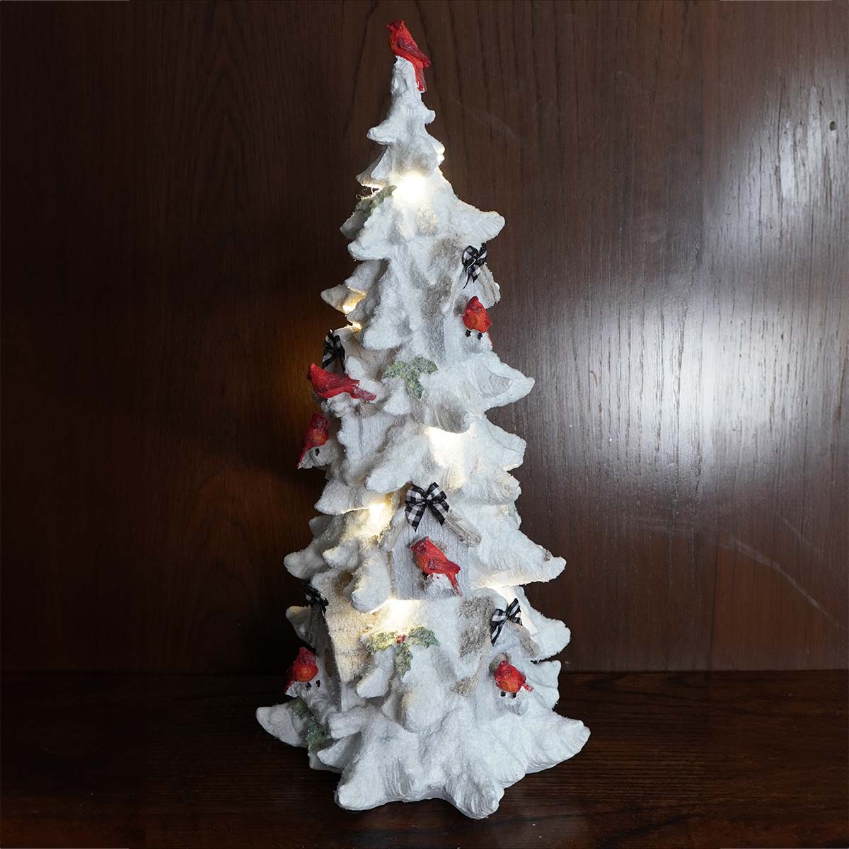 White ceramic Christmas tree decorated with red cardinals and small lights.