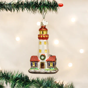 A festive glass lighthouse ornament with red and gold accents featuring a small house for figural decor or tree toppers