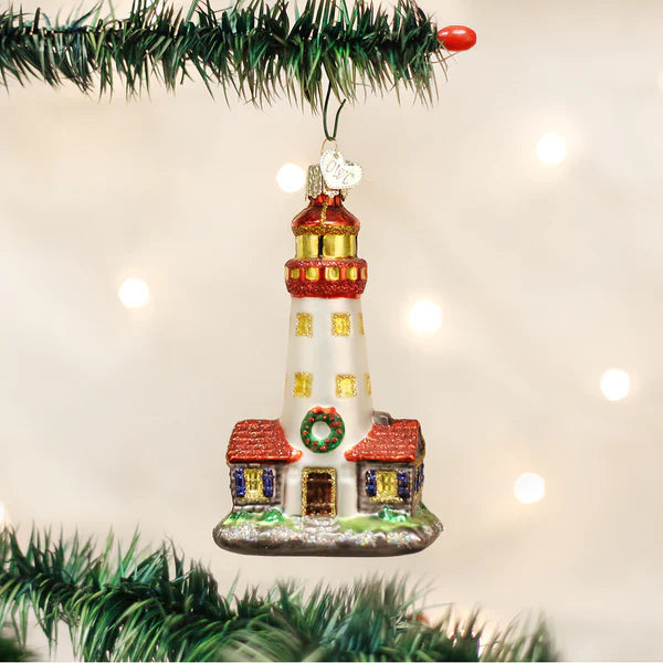 A festive glass lighthouse ornament with red and gold accents featuring a small house for figural decor or tree toppers