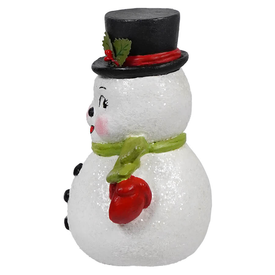 Cheerful snowman figurine wearing a black top hat and green scarf.