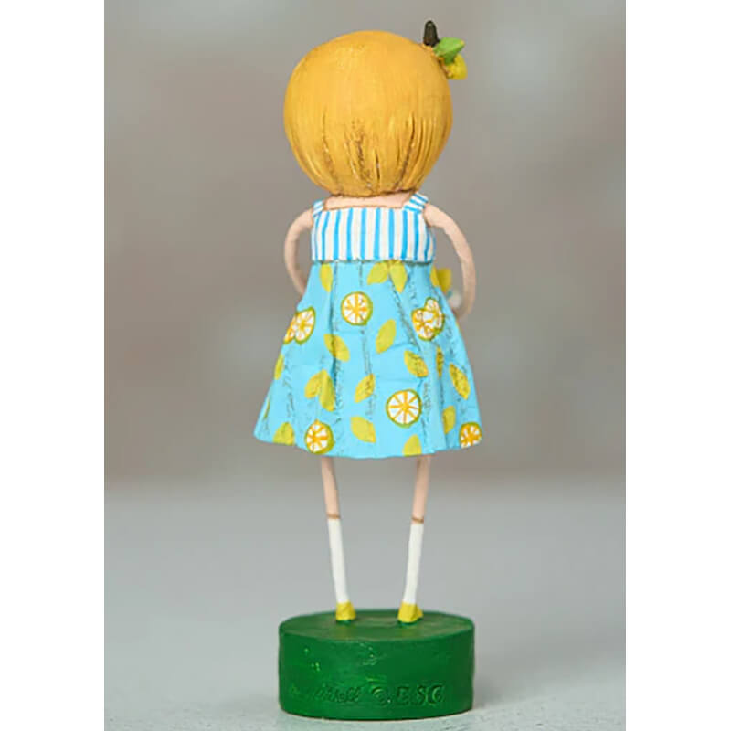 Decorative doll figure wearing a blue lemon-print dress with yellow hair standing on a green base.