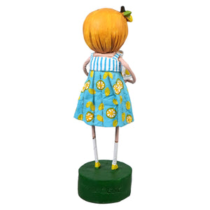 A whimsical lori mitchell figurine of a girl with orange hair in a blue dress decorated with yellow lemon slices from lily anne’s lemons