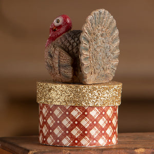 A rustic turkey on box figurine with a red head and brown body sits on a plaid box perfect for thanksgiving decor