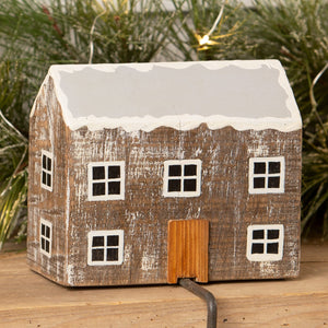 Rustic wooden log cabin stocking holder with weathered texture white windows orange door and snowy roof for christmas stockings