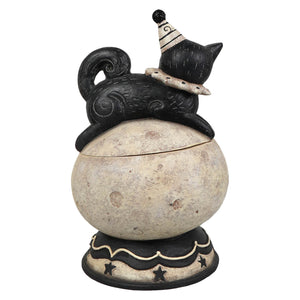 Black ceramic cat figurine wearing striped party hat sitting on textured off white jack o lantern base with stars feet