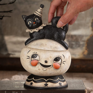 Black cat figurine with striped party hat and polka dot collar on cream smiling moon container loony jack o lantern