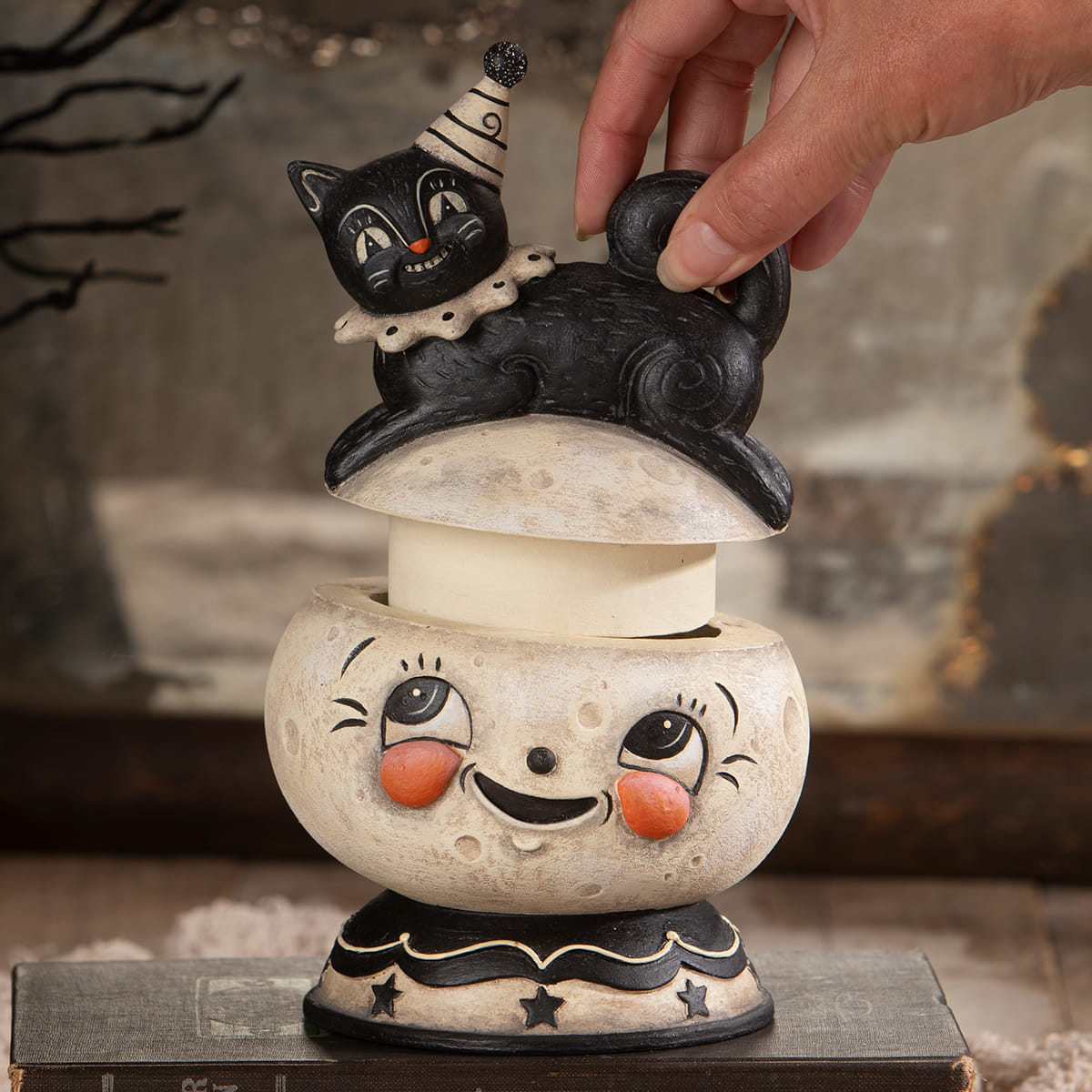 Black cat figurine with striped party hat and white collar on smiling moon candle holder for jack o lantern decor