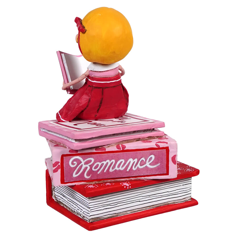 Stack of red and pink romance books with an orange on top.