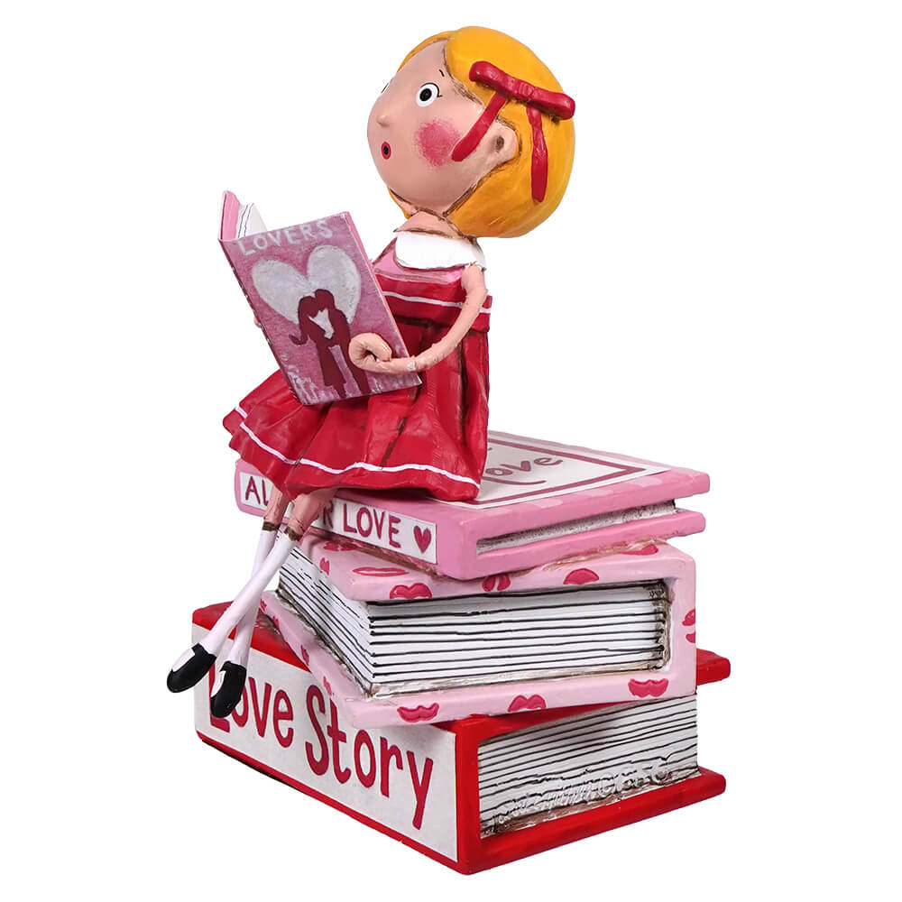 A decorative figurine reading a love story while sitting atop a stack of pink and red books.