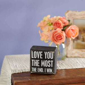 Black wooden win box sign with white stenciled love you the most the end text perfect for valentine’s day tabletop decor