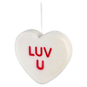White heart-shaped candy with ’LUV U’ written in red letters.