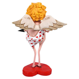 A whimsical angel figurine with curly yellow hair wearing a heart-patterned dress standing on a red heart base.