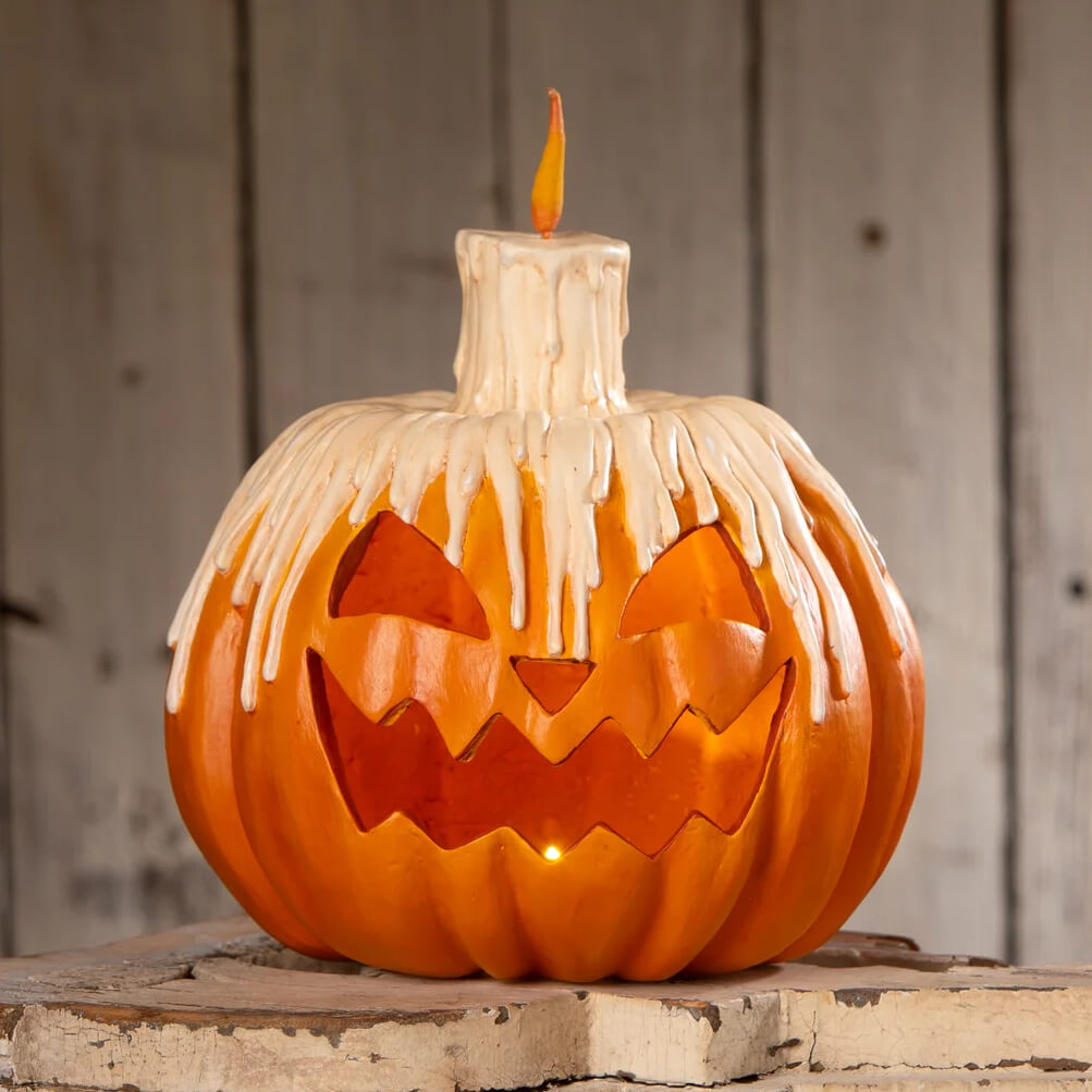 Melting midnight glow pumpkin with orange glow pumpkin design features white candle top and dripping wax effect