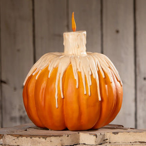Orange melting midnight glow pumpkin decoration with white candle design and orange flame showing dripping wax effect