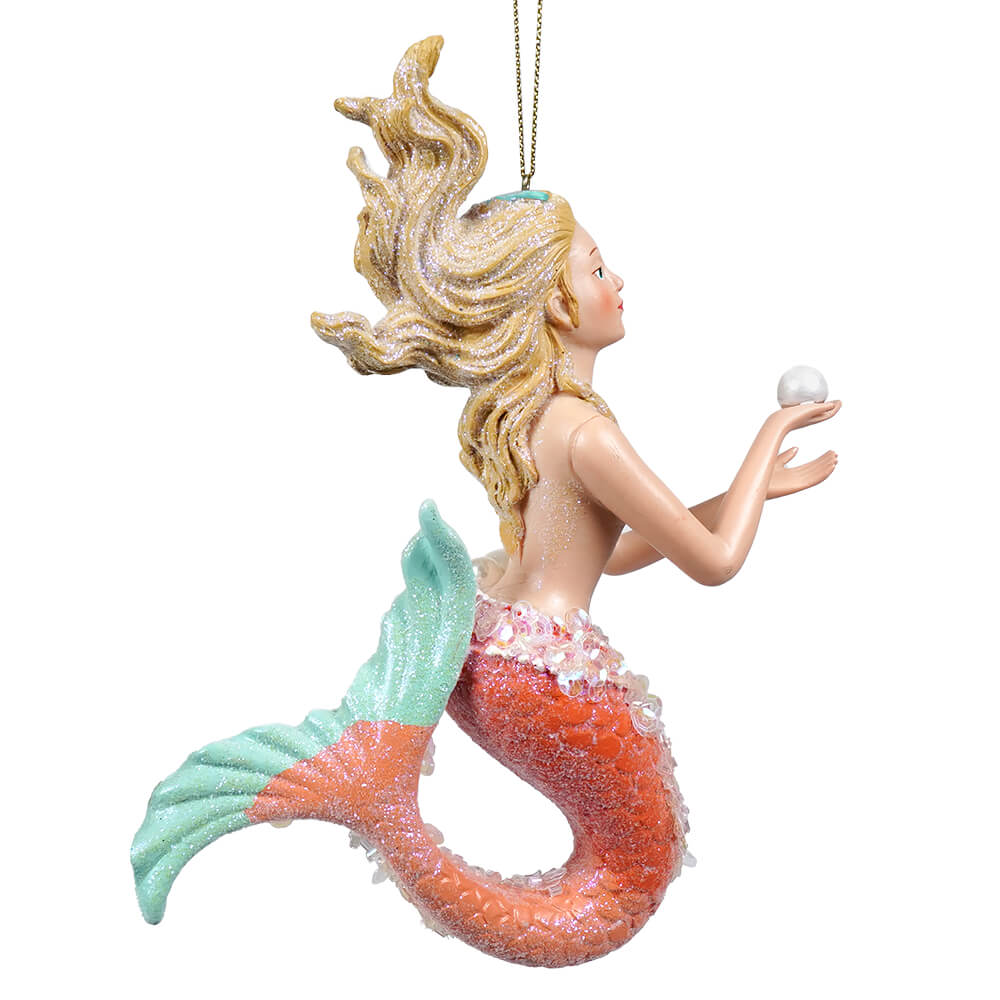 A glittery resin mermaid ornament with blonde hair, turquoise and orange tail holding a pearl december diamonds ornament