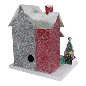 A merry bright glitter cottage birdhouse with red and silver sparkly exterior and snow-dusted roof with chimney